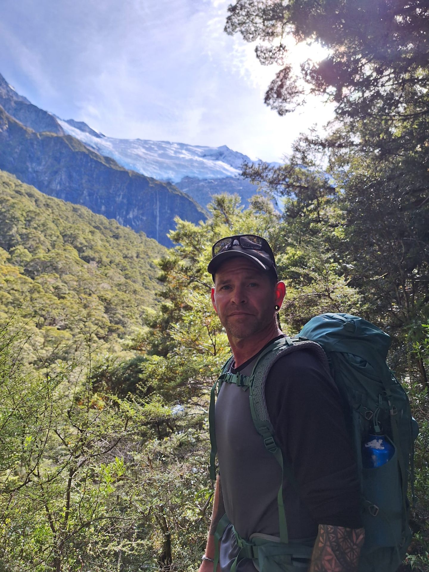 Hiking with a backpack in front of a glacier and forested mountain valley